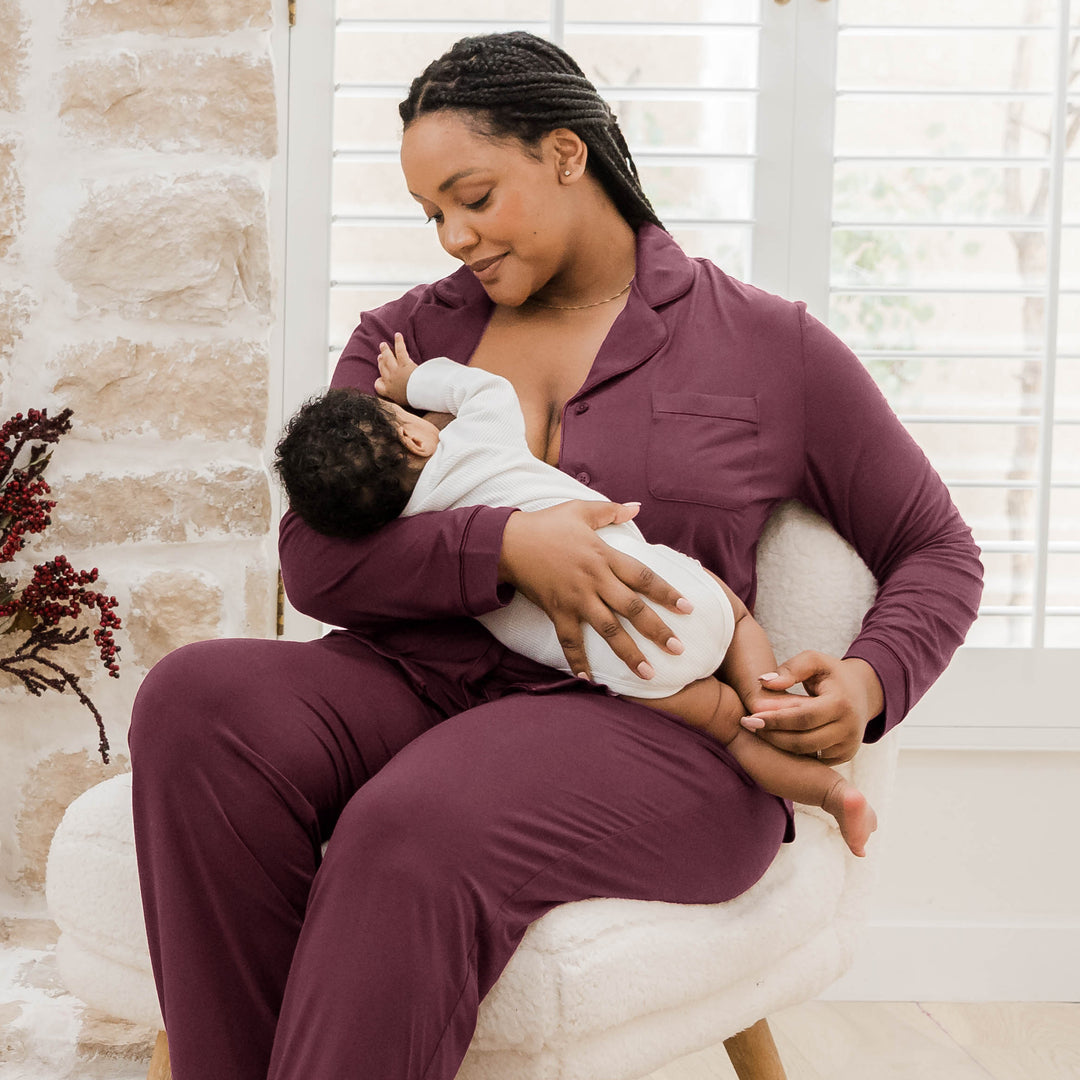 Model wearing the Clea Bamboo Long Sleeve Pajama Set in Fig feeding her baby.